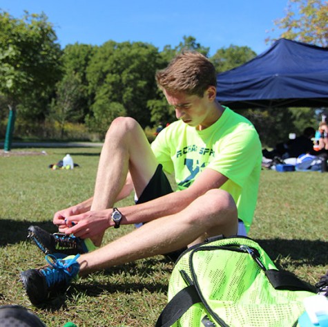 Charlie Kern, sophomore, laces up his racing spikes in preparation for the start of the varsity race.
