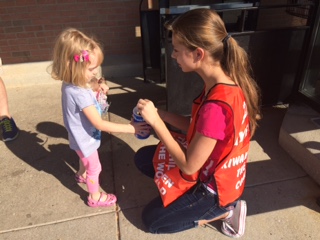 Key Club member Esther Povh giving a little girl peanuts in exchange for a Kiwanis donation at Jewel.