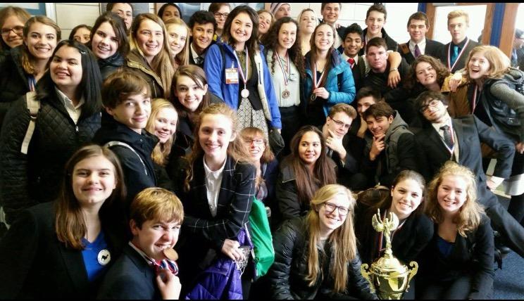 The York Speech Team smiling happily next to their third consecutive first place trophy. 