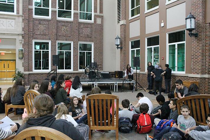 A crowd of students gather and wait for open mic performances. 