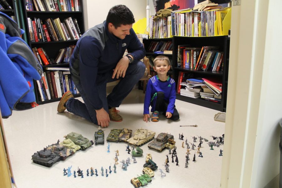 Social studies teacher, Mr. Riskus, lines up army men for his son to play with. 