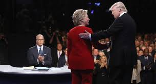 During the ceremonial handshake, debate moderator Lester Holt applauds both presidential candidates, Secretary of State Hillary Clinton, and Republican Presidential Nominee Donald Trump.