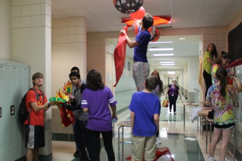 Jithu Thomas and Alex Johnson, juniors, show off one of their favorite parts of the hallway, their classroom dragon, while the rest of the club helps hang lanterns from the ceiling.