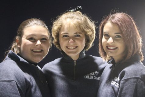 Seniors Julia McColl and Mikayla Castora and junior Madeleine DeGrace from the color guard team, stay excited for the halftime show. 