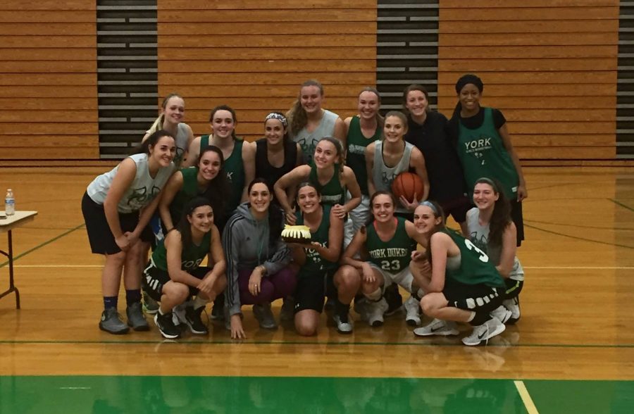 The Varsity Girls Basketball Team shows their camaraderie as they gather close for a team picture at practice.