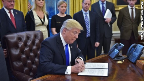President Donald Trump signs an executive order in the Oval Office.