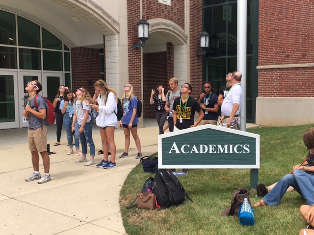 Student gather outside the academic entrance to watch the eclipse.