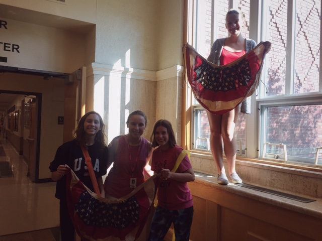 Sophomore Haley Grane (left), Freshman Kathryn King, Sophomore Avie Magner, and Freshman Tessa Olson hang American flag banners to decorate the Drama Club hallway after school