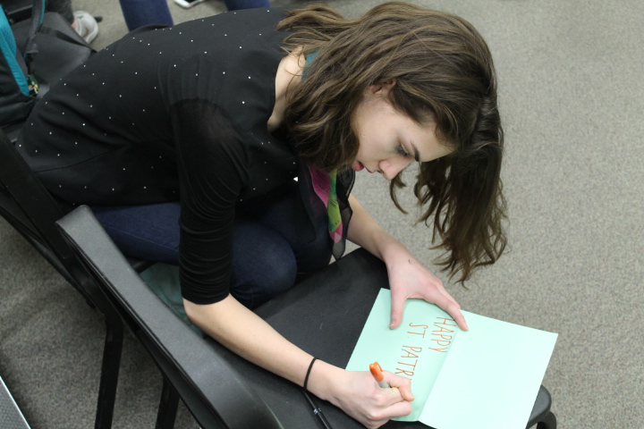 Junior Jacki Riek writing a card for a nursing home, using all Irish colors, to make it as festive and joyful as possible for the recipients.