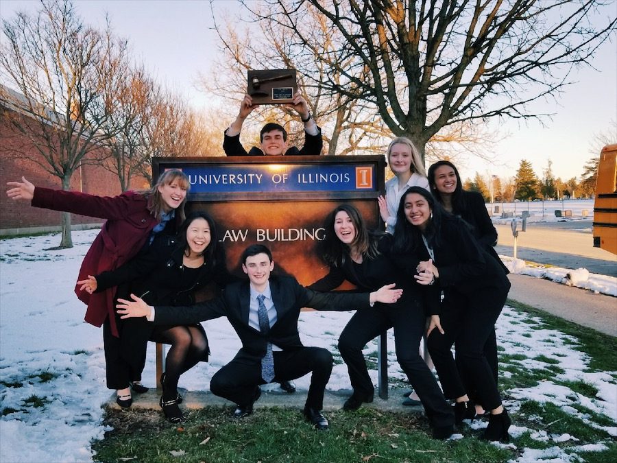 The varsity team basks in their victory as they pose around the University of Illinois College of Law sign.