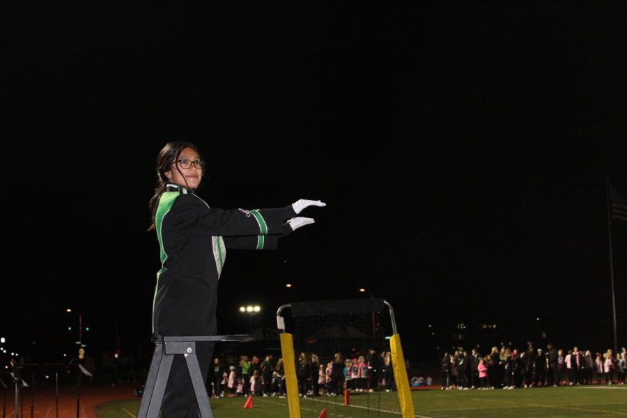 Senior drum major Lily __ leads the marching band during their fourth halftime show of the year. 