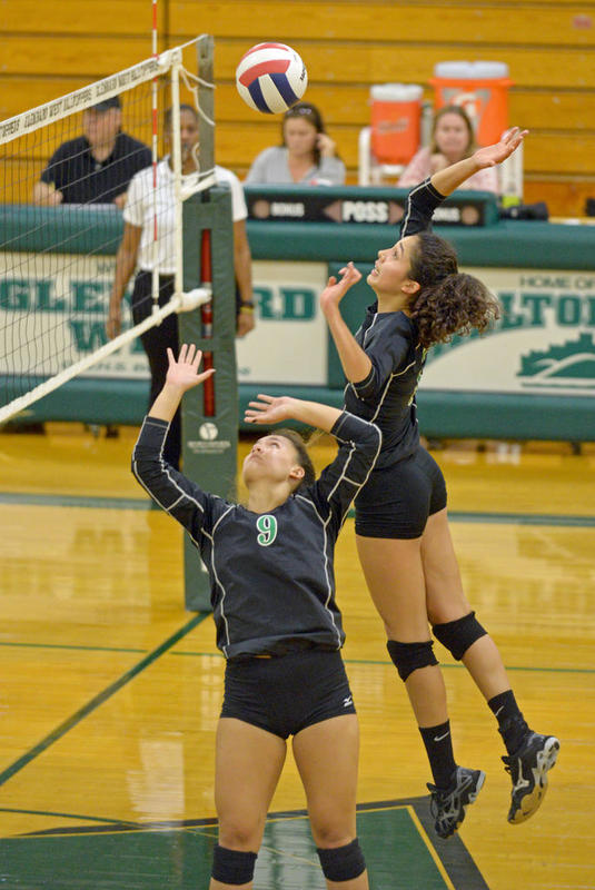 Seniors Samantha Kao and Asha Labine jump up to get the ball over the net and score a point in their comeback game against Glenbard West. 