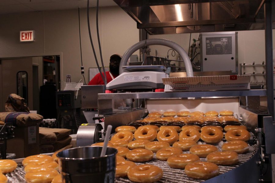 A conveyor belt carries thousands of donuts each day, dousing them in the delicious, well known glaze. 