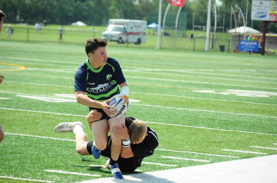 Sophomore Patrick Cote running the ball before a tackle during the Rugby Illinois Championship.