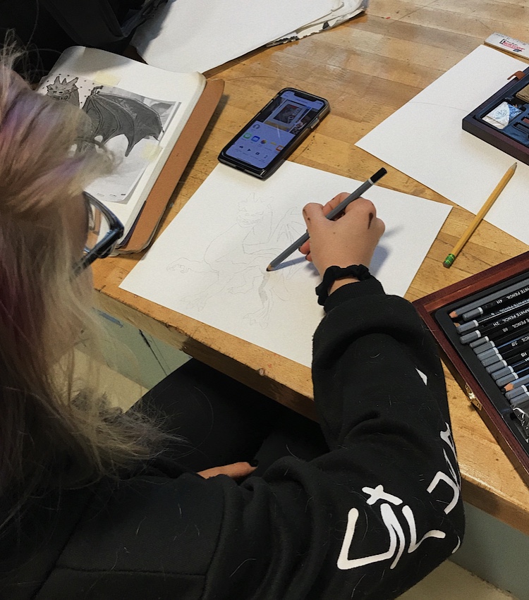 Senior Katherine Gobber works on a charcoal drawing of a dragon in AP art class.