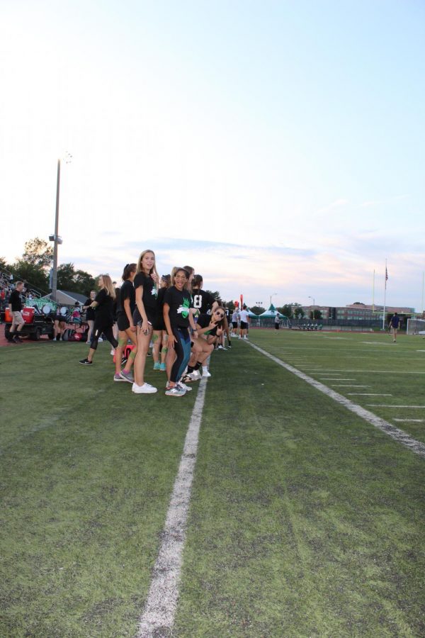 Senior girls line up on the sideline to cheer on their teammates.