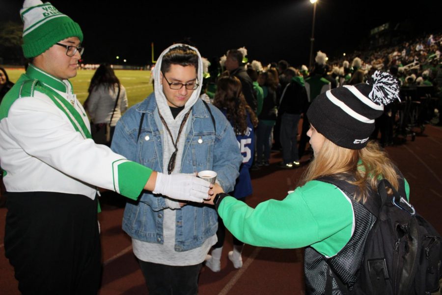 Student Body President Murphy McFarlane gives hot chocolate to band members to warm their spirits.