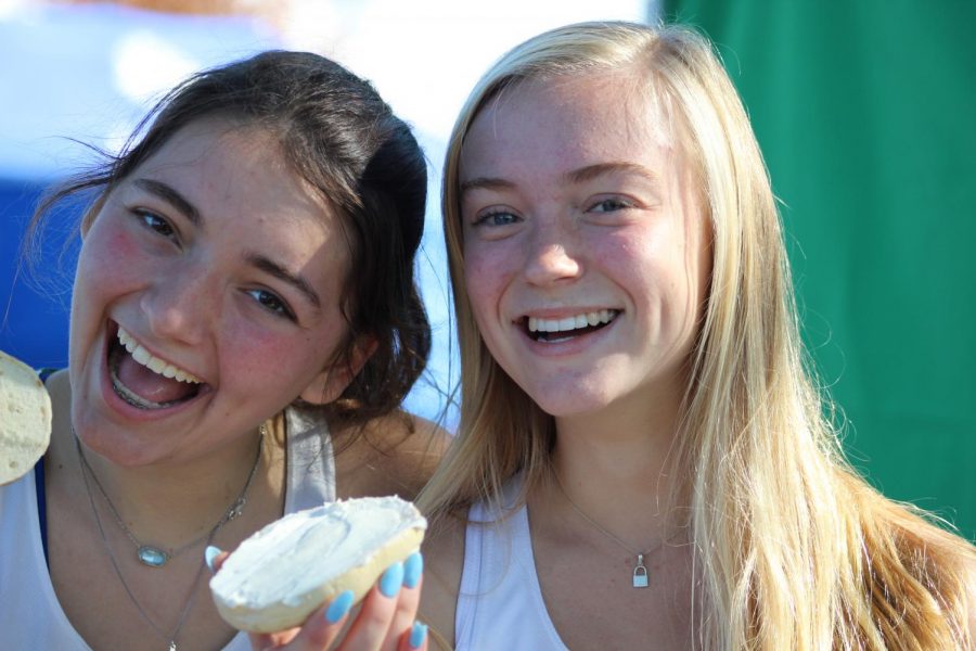 Sophomores Emily Baker and Lucy Baird enjoy a bagel from the bagel table after completing their race. Oct. 19, 2019.