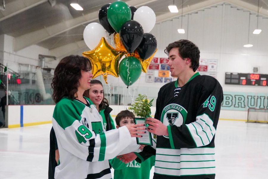 Senior Declan Quinn skates flower over to his family as the first of five to experience a senior night.  