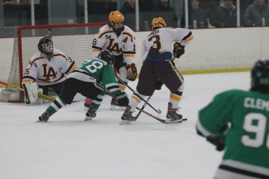 Sophomore Bobby Plummer steals the puck from Loyola defensemen right in front of the net. 