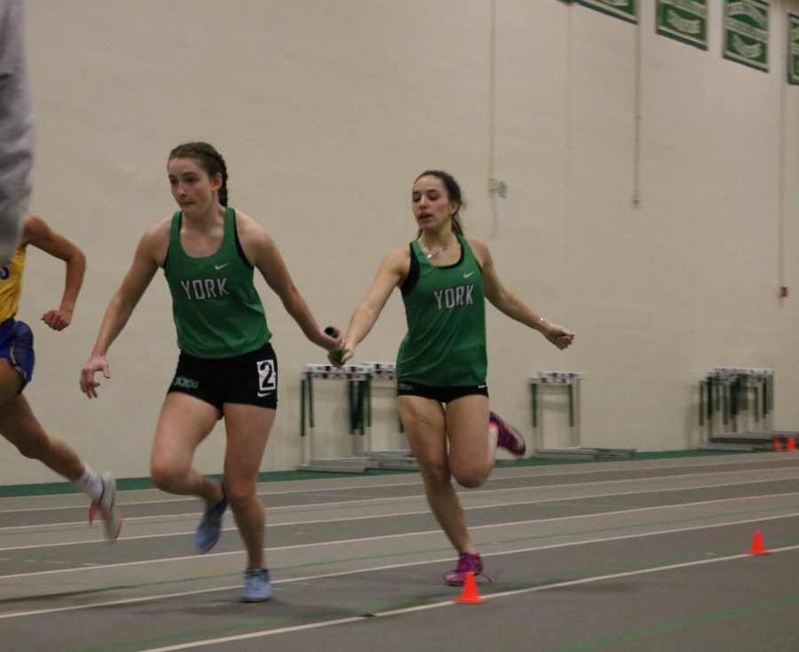 Junior Bianca Spedale exchanges the baton to teammate junior Lauren Keith in the 4X200m relay. 