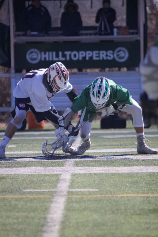 Senior Harrison Proud takes a face-off in a game last spring, the 2019 season, against the Glenbard West Hilltoppers.