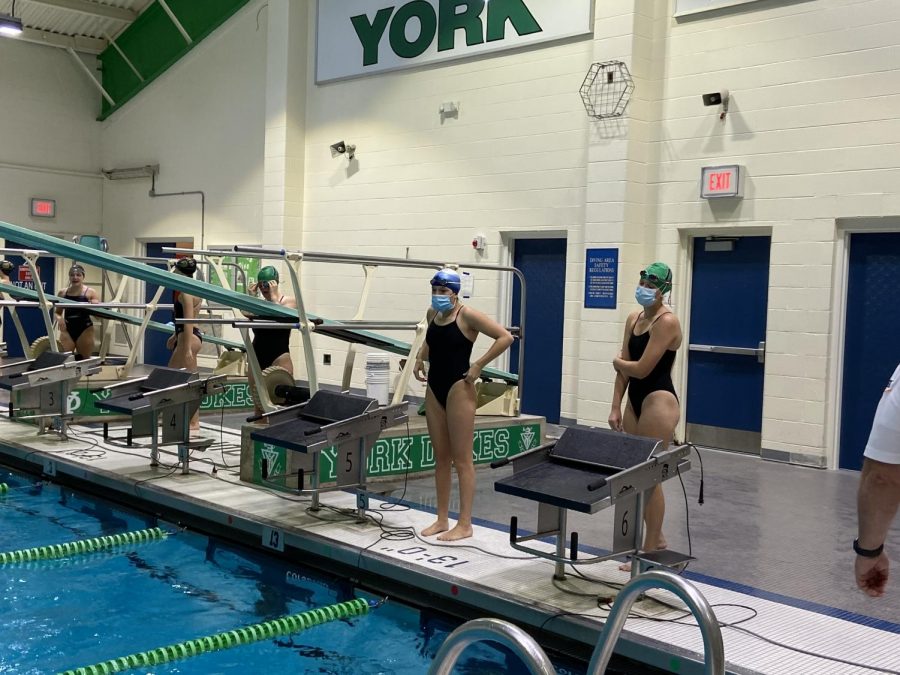 Junior Kyra Szczepanek (left) and Senior Paige Palermo (right) wear their mask up until the very last second before they dive off the block to begin their race. 
