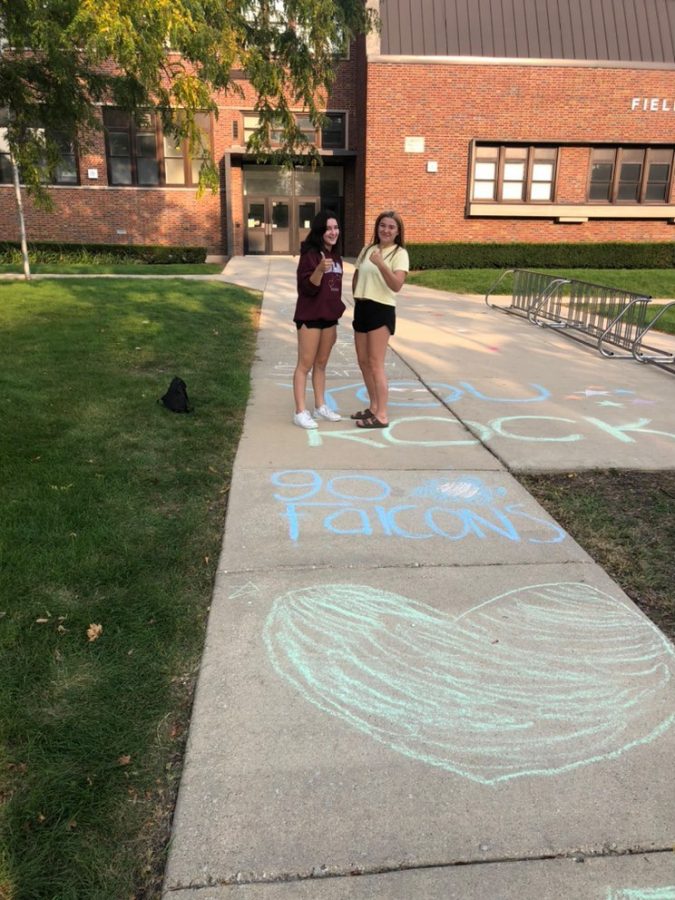 Sophmores Ashley Simonis (left) and Cassidy Wehrle (right) flash some big thumbs up while displaying their colorful drawings made in front of Field Elementary School. 