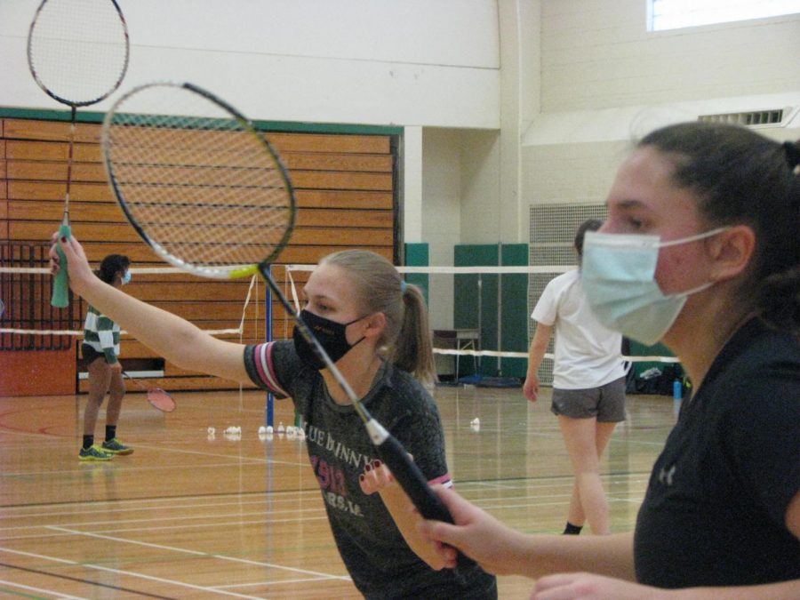 On Friday, Feb. 26, juniors and Junior Varsity Badminton team players, Emily Hyink and Elle Jacobsthal, prepare themselves for the quick return of the birdie in a practice doubles match before their meet with Downers Grove South.