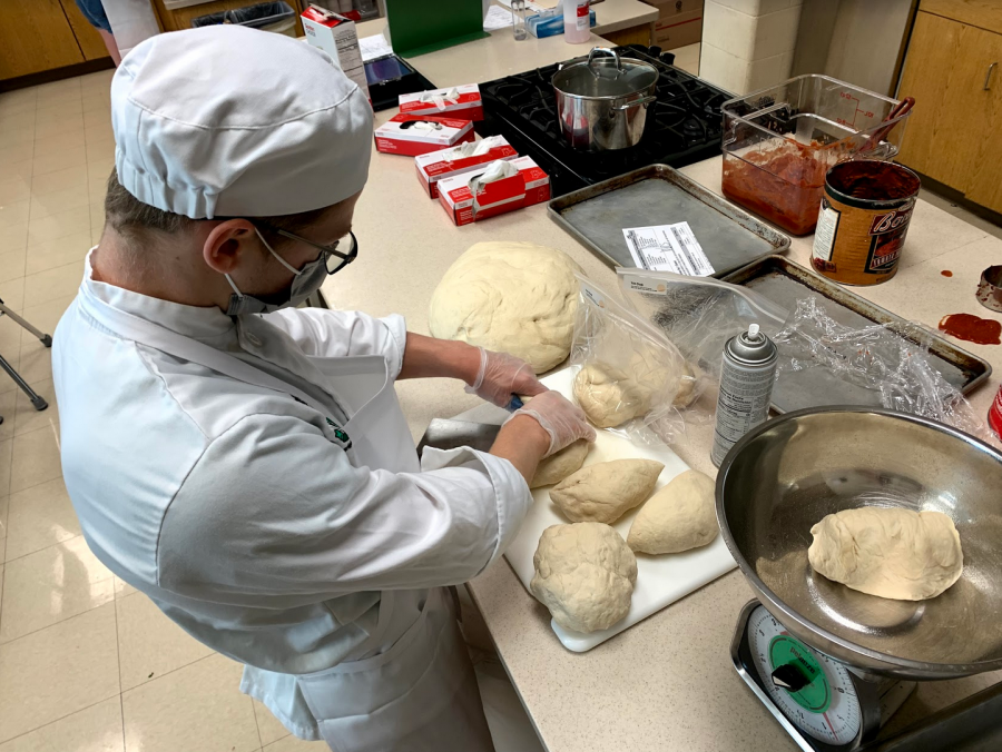 Senior Nolan Fazzini weighs dough to be sold in pizza kits. Food is prepared by members of the program in the week leading up to the event. (Finnegan Belleau)