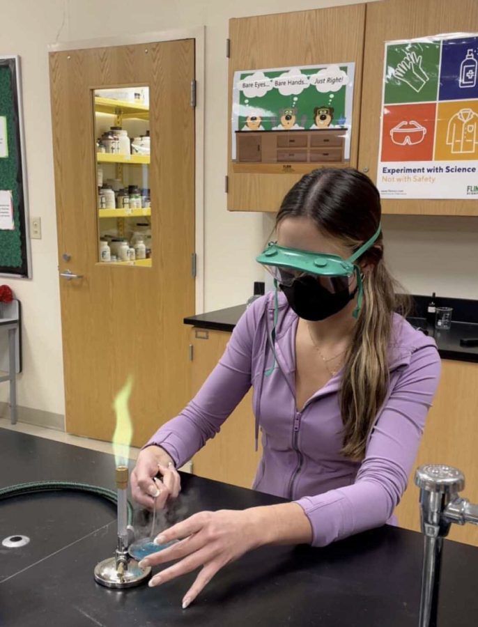 Senior Lexie Sidoryk works on a science experiment (burning copper sulfate) in her AP Chemistry class.