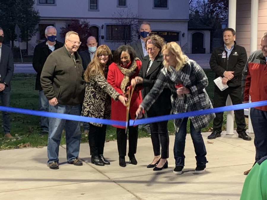 Superintendent Keisha Campbell cuts a ribbon in front of the new Bridges Transition Center with wooden scissors to commemorate the official opening. (Finnegan Belleau)
