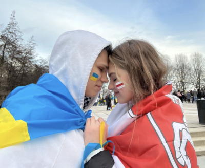 Darya Rohava wraps herself in a Belarussian flag as she joins her boyfriend Stas Reymer in a Ukrainian flag for a protest in Chicago.