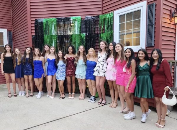 A large group of freshman girls ready to go to homecoming posing for a picture at a before party.