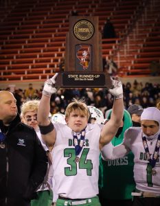 Senior football captain Jimmy Conners holds the trophy high after the team was named Class 8A State Runners-Up.